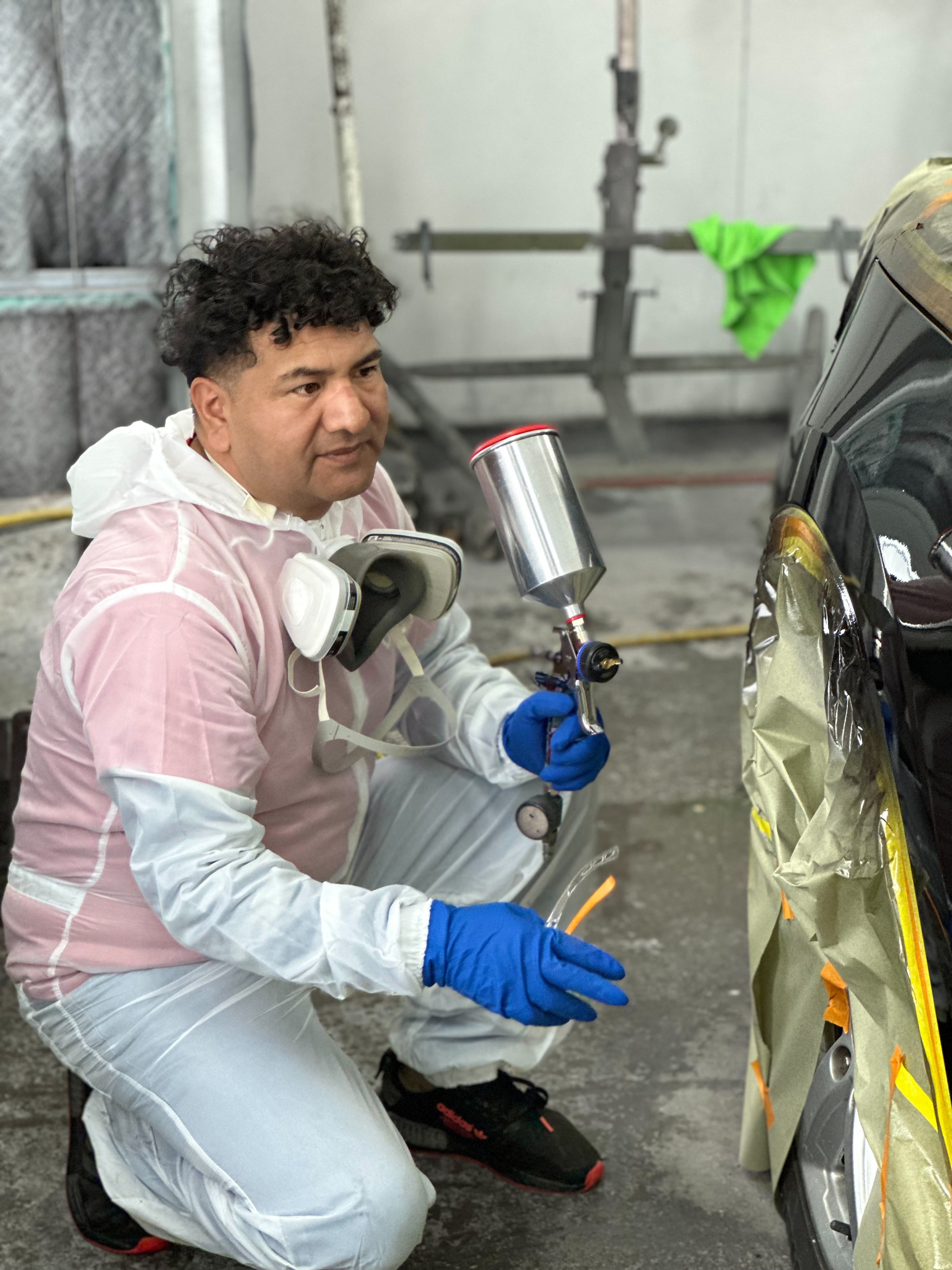 Technician sanding and repairing a car body panel in the shop