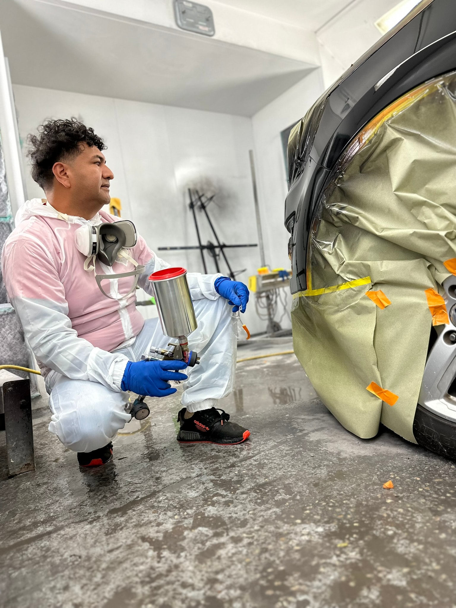 Mechanic sanding a car body panel before refinishing