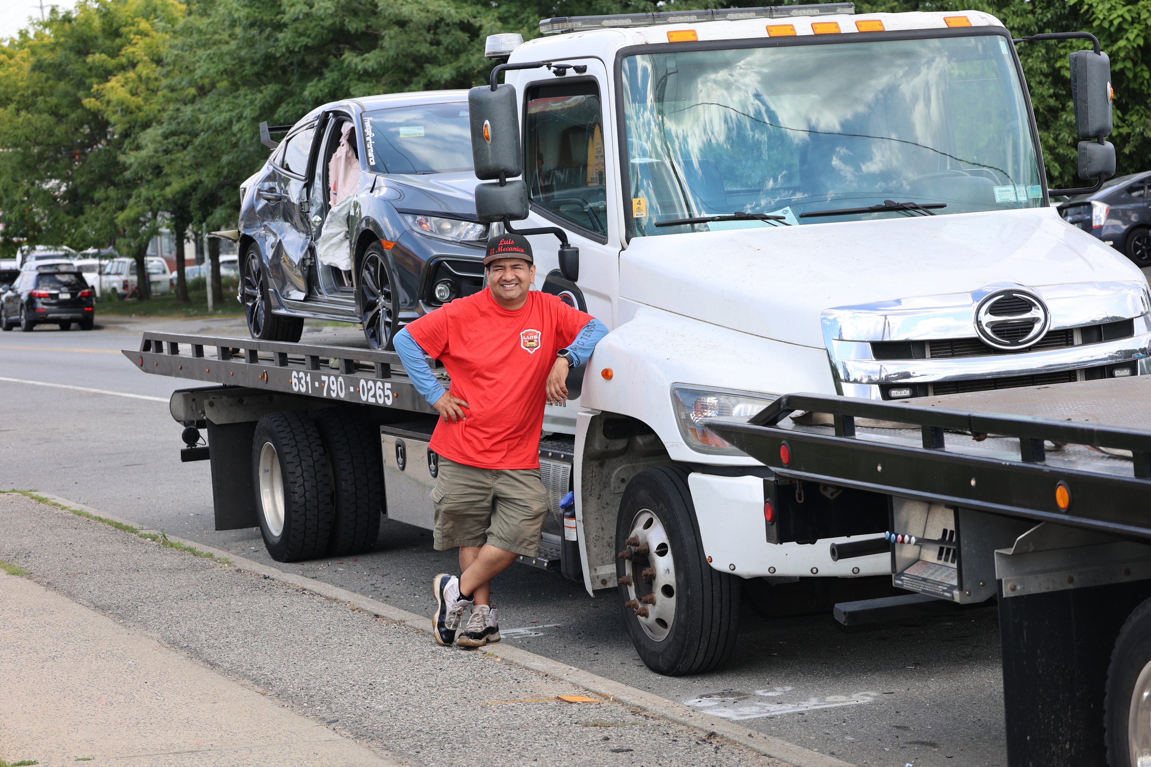 Tow truck operator securing a damaged vehicle for transport