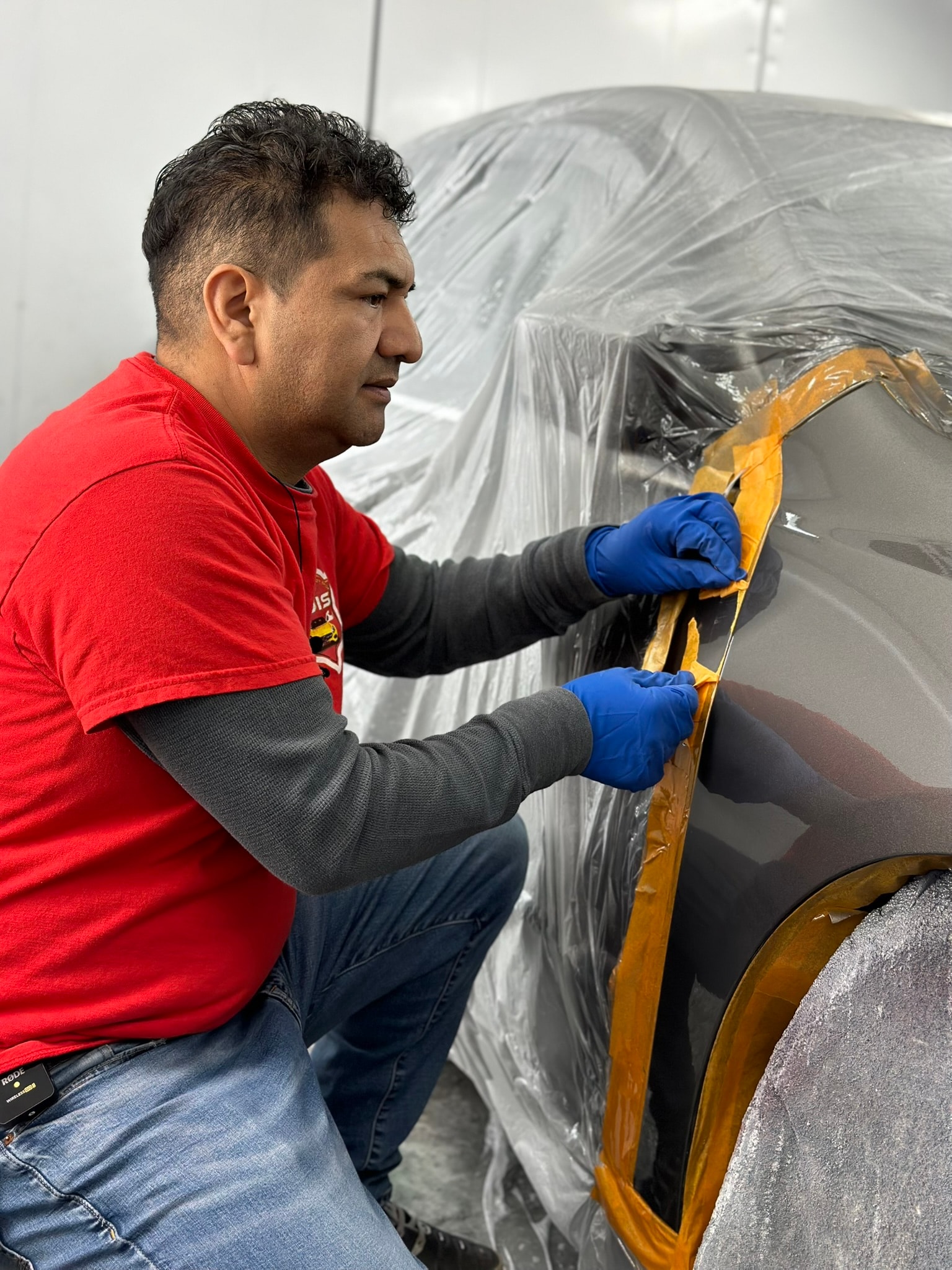 Painter applying fresh metallic paint in a professional spray booth